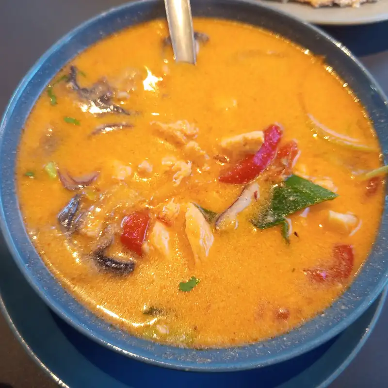 Zupa curry z krewetkami i papryką w niebieskiej misce